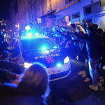 Supporters of France react next to a police car at the end of the World Cup semifinal soccer match between France and Morocco, in Paris, Wednesday, Dec. 14, 2022. (AP Photo/Thibault Camus)