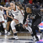 Connecticut's Nika Muhl (10) and Providence's Janai Crooms, right, chase the ball in the first half of an NCAA college basketball game, Friday, Dec. 2, 2022, in Storrs, Conn. (AP Photo/Jessica Hill)
