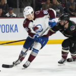 Colorado Avalanche center Denis Malgin (81) skates with the puck in front of Arizona Coyotes defenseman Shayne Gostisbehere (14) during the second period of an NHL hockey game in Tempe, Ariz., Tuesday, Dec. 27, 2022. (AP Photo/Ross D. Franklin)