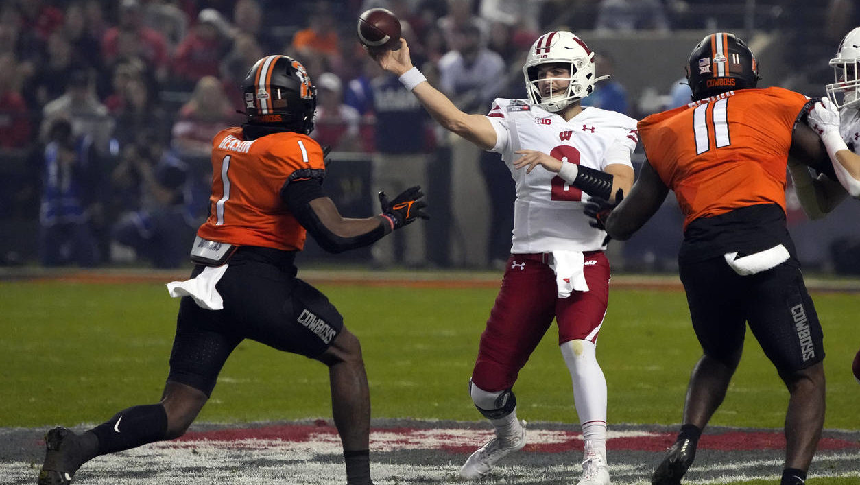 Wisconsin quarterback Chase Wolf (2) throws a pass from between Oklahoma State linebackers Xavier B...