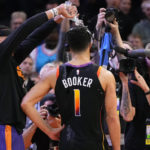 Phoenix Suns guard Devin Booker (1) has water poured on his head by teammate Damion Lee after an NBA basketball game against the New Orleans Pelicans, Saturday, Dec. 17, 2022, in Phoenix. The Suns defeated the Pelicans 118-114. (AP Photo/Matt York)