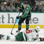 Dallas Stars defenseman Esa Lindell (23) controls the puck as Minnesota Wild center Connor Dewar (26) goes down during the first period of an NHL hockey game in Dallas, Sunday, Dec. 4, 2022. (AP Photo/LM Otero)