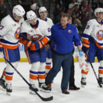 New York Islanders defenseman Alexander Romanov (28) gets helped off the ice by teammates and trainer in the third period during an NHL hockey game against the Arizona Coyotes, Friday, Dec. 16, 2022, in Tempe, Ariz. Arizona won 5-4. (AP Photo/Rick Scuteri)