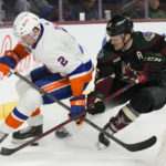 New York Islanders defenseman Robin Salo (2) and Arizona Coyotes right wing Christian Fischer (36) fight for the puck in the third period during an NHL hockey game, Friday, Dec. 16, 2022, in Tempe, Ariz. Arizona won 5-4. (AP Photo/Rick Scuteri)