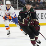 Arizona Coyotes right wing Clayton Keller (9) carries the puck towards the goal past New York Islanders left wing Anders Lee in the third period during an NHL hockey game, Friday, Dec. 16, 2022, in Tempe, Ariz. Arizona won 5-4. (AP Photo/Rick Scuteri)