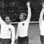 
              FILE -  England's captain Bobby Moore, centre, is flanked by team mate George Cohen, left, and Geoff Hurst as they wave to the crowd at the end of the Football World Cup semi-final match at Wembley, London, on July 26, 1966. George Cohen, the right-back for England World Cup-winning team of 1966, has died aged 83, his former club Fulham have announced on Friday, Dec. 23, 2022. (AP Photo/Bippa, File)
            