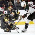 Vegas Golden Knights right wing Mark Stone (61) falls to the ice in front of Arizona Coyotes left wing Lawson Crouse (67) during the first period of an NHL hockey game Wednesday, Dec. 21, 2022, in Las Vegas. (AP Photo/Chase Stevens)