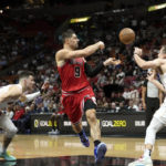 Chicago Bulls center Nikola Vucevic (9) passes the ball as Miami Heat guard Tyler Herro, left, and forward Duncan Robinson, right, defend during the first half of an NBA basketball game, Tuesday, Dec. 20, 2022, in Miami. (AP Photo/Lynne Sladky)