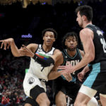 Minnesota Timberwolves guard Wendell Moore Jr., left, passes the ball as Portland Trail Blazers forward Trendon Watford, center, and forward Drew Eubanks, right, defend during the first half of an NBA basketball game in Portland, Ore., Saturday, Dec. 10, 2022. (AP Photo/Steve Dykes)