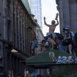 
              Soccer fans continue to celebrate outside the Casa Rosada presidential palace, despite waiting for hours for a homecoming parade for the players who won the World Cup title that was abruptly cut short, in Buenos Aires, Argentina, Tuesday, Dec. 20, 2022. A parade to celebrate the Argentine World Cup champions was abruptly cut short Tuesday as millions of people poured onto thoroughfares, highways and overpasses in a chaotic attempt to catch a glimpse of the national team. (AP Photo/Rodrigo Abd)
            