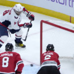 Washington Capitals' Alex Ovechkin keeps his eye on the puck just before scoring his second goal of the game as Chicago Blackhawks' Jake McCabe and Jack Johnson (8) defend during the first period of an NHL hockey game Tuesday, Dec. 13, 2022, in Chicago. (AP Photo/Charles Rex Arbogast)