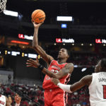 
              Western Kentucky center Jamarion Sharp (33) shoots over Louisville guard El Ellis (3) and guard Mike James (1) during the first half of an NCAA college basketball game in Louisville, Ky., Wednesday, Dec. 14, 2022. (AP Photo/Timothy D. Easley)
            