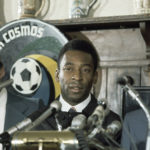 FILE -  New York Cosmos' Pele stands with others at news conference in New York on June 10, 1975. Dozens of meetings over four years led to Pelé agreeing to sign with Cosmos in June 1975. His 2 1/2 seasons in New York elevated the sport, putting U.S. soccer on a path to hosting the World Cup in 1994 and launching Major League Soccer two years later. (AP Photo, File)