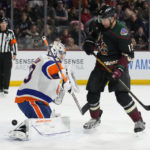 New York Islanders goaltender Semyon Varlamov, front left, makes a save in front of Arizona Coyotes left wing Nick Ritchie (12) in the first period during an NHL hockey game, Friday, Dec. 16, 2022, in Tempe, Ariz. (AP Photo/Rick Scuteri)