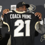 Deion Sanders holds up a jersey before speaking after being introduced as the new head football coach at the University of Colorado during a news conference Sunday, Dec. 4, 2022, in Boulder, Colo. Sanders left Jackson State University after three seasons at the helm of the school's football team. (AP Photo/David Zalubowski)