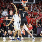 Cincinnati guard David DeJulius (5) goes up to shoot a 3-point basket as he is fouled by Xavier guard Desmond Claude (1) during the second half of an NCAA college basketball game, Saturday, Dec. 10, 2022, in Cincinnati. (AP Photo/Aaron Doster)