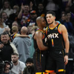 Phoenix Suns guard Chris Paul embraces guard Devin Booker (1) after Booker made a basket during the second half of an NBA basketball game against the New Orleans Pelicans, Saturday, Dec. 17, 2022, in Phoenix. The Suns defeated the Pelicans 118-114. (AP Photo/Matt York)