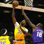 Los Angeles Lakers center Damian Jones (30) shoots over Lakers forward Wenyen Gabriel (35) and Phoenix Suns center Bismack Biyombo (18) during the first half of an NBA basketball game, Monday, Dec. 19, 2022, in Phoenix. (AP Photo/Rick Scuteri)