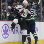 Arizona Coyotes' Barrett Hayton (29) and Vancouver Canucks' Oliver Ekman-Larsson (23) collide during the second period of an NHL hockey game Saturday, Dec. 3, 2022, in Vancouver, British Columbia. (Darryl Dyck/The Canadian Press via AP)