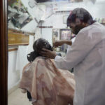 A barber shaves a customer at a narrow ally at the Souq Waqif Market, in Doha, Qatar, Friday, Dec. 2, 2022. (AP Photo/Eugene Hoshiko)