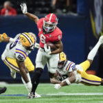Georgia running back Kenny McIntosh (6) tries to escape from LSU safety Major Burns (28) and defensive tackle Jaquelin Roy (99) in the second half of the Southeastern Conference Championship football game Saturday, Dec. 3, 2022 in Atlanta. (AP Photo/John Bazemore)