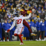 Washington Commanders wide receiver Jahan Dotson (1) catches a pass over New York Giants cornerback Jason Pinnock (27) during the second half of an NFL football game, Sunday, Dec. 18, 2022, in Landover, Md. (AP Photo/Nick Wass)