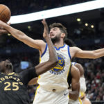 Golden State Warriors guard Ty Jerome (10) tries to swat the ball away from Toronto Raptors forward Chris Boucher (25) during first-half NBA basketball game action in Toronto, Sunday, Dec. 18, 2022. (Frank Gunn/The Canadian Press via AP)