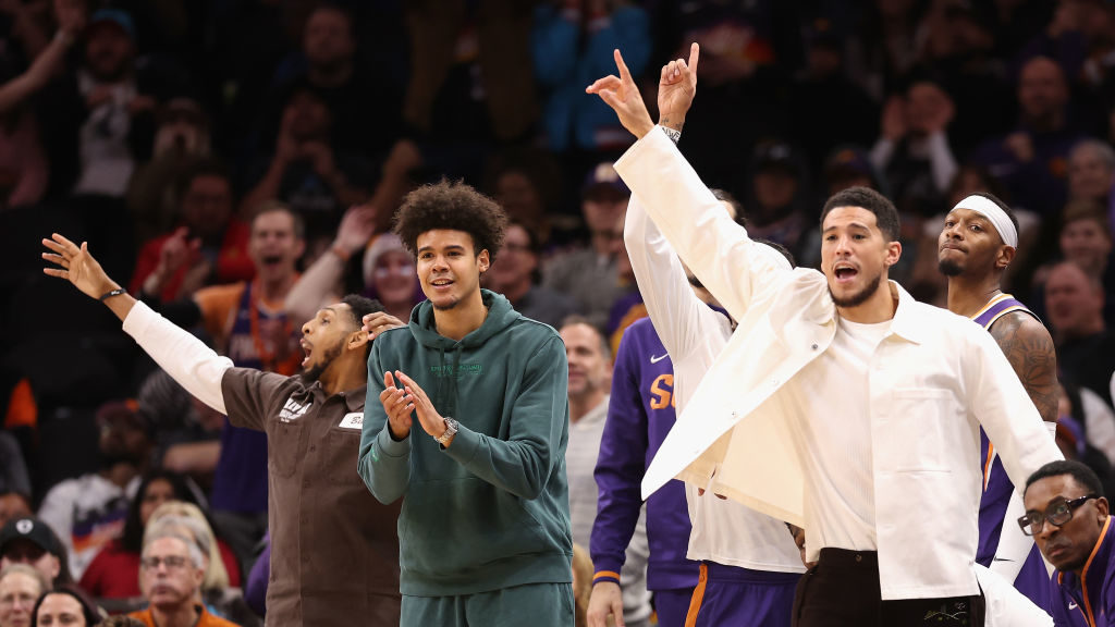 (R-L) Devin Booker #1, Cameron Johnson #23 and Cameron Payne #15 of the Phoenix Suns react on the b...