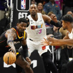 Phoenix Suns center Deandre Ayton, left, tries to control the ball in front of Miami Heat center Bam Adebayo (13) and forward Jimmy Butler, right, during the first half of an NBA basketball game in Phoenix, Friday, Jan. 6, 2023. (AP Photo/Ross D. Franklin)
