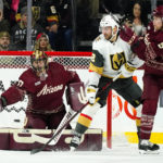 Arizona Coyotes goaltender Karel Vejmelka, left, reaches out to make a save as Vegas Golden Knights right wing Michael Amadio (22) and Coyotes defenseman Jakob Chychrun, right, battle for position during the first period of an NHL hockey game in Tempe, Ariz., Sunday, Jan. 22, 2023. (AP Photo/Ross D. Franklin)