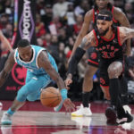 Toronto Raptors guard Gary Trent Jr. (33) and Charlotte Hornets guard Terry Rozier reach for the ball during the first half of an NBA basketball game Thursday, Jan. 12, 2023, in Toronto. (Frank Gunn/The Canadian Press via AP)