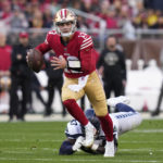 San Francisco 49ers quarterback Brock Purdy, top, scrambles away from Seattle Seahawks defensive tackle Poona Ford during the first half of an NFL wild card playoff football game in Santa Clara, Calif., Saturday, Jan. 14, 2023. (AP Photo/Godofredo A. Vásquez)