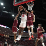 
              Houston's Tramon Mark (12) goes up for a shot as Temple's Nick Jourdain (11) and Zach Hicks, left, defend during the first half of an NCAA college basketball game Sunday, Jan. 22, 2023, in Houston. (AP Photo/David J. Phillip)
            