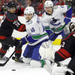 Vancouver Canucks' Elias Pettersson (40) tries to maintain control of the puck while battling Carolina Hurricanes' Seth Jarvis (24) in front of Hurricanes goaltender Pyotr Kochetkov (52) during the first period of an NHL hockey game in Raleigh, N.C., Sunday, Jan. 15, 2023. (AP Photo/Karl B DeBlaker)