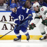 Tampa Bay Lightning center Brayden Point (21) carries the puck ahead of Minnesota Wild left wing Marcus Foligno (17) during the first period of an NHL hockey game Tuesday, Jan. 24, 2023, in Tampa, Fla. (AP Photo/Chris O'Meara)