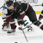 Arizona Coyotes center Nick Bjugstad (17) gets hooked by San Jose Sharks right wing Kevin Labanc (62) during the first period of an NHL hockey game in Tempe, Ariz., Tuesday, Jan. 10, 2023. (AP Photo/Ross D. Franklin)