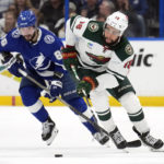 Minnesota Wild left wing Jordan Greenway (18) breaks out ahead of Tampa Bay Lightning right wing Nikita Kucherov (86) during the first period of an NHL hockey game Tuesday, Jan. 24, 2023, in Tampa, Fla. (AP Photo/Chris O'Meara)