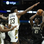 Milwaukee Bucks' Jrue Holiday (21) shoots against Indiana Pacers' Aaron Nesmith (23) and Myles Turner, left, during the second half of an NBA basketball game Monday, Jan. 16, 2023, in Milwaukee. (AP Photo/Aaron Gash)