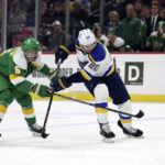 Minnesota Wild defenseman Jake Middleton (5) and St. Louis Blues left wing Brandon Saad (20) go after the puck during the first period of an NHL hockey game Sunday, Jan. 8, 2023, in St. Paul, Minn. (AP Photo/Stacy Bengs)