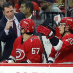 Carolina Hurricanes coach Rod Brind'Amour, left, talks with Max Pacioretty (67) and Sebastian Aho (20) during the second period of the team's NHL hockey game against the Nashville Predators in Raleigh, N.C., Thursday, Jan. 5, 2023. (AP Photo/Karl B DeBlaker)