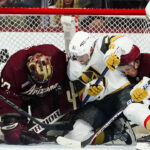 Arizona Coyotes goaltender Karel Vejmelka, left, makes a save against a shot by Vegas Golden Knights center Byron Froese (51) as Coyotes defenseman Troy Stecher, second from right, and Golden Knights right wing Keegan Kolesar (55) look on during the third period of an NHL hockey game in Tempe, Ariz., Sunday, Jan. 22, 2023. (AP Photo/Ross D. Franklin)
