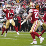 San Francisco 49ers quarterback Brock Purdy (13) throws touchdown pass to running back Christian McCaffrey (23) in front of Seattle Seahawks linebacker Bruce Irvin (51) during the first half of an NFL wild card playoff football game in Santa Clara, Calif., Saturday, Jan. 14, 2023. (AP Photo/Godofredo A. Vásquez)