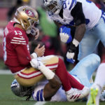 San Francisco 49ers quarterback Brock Purdy (13) is sacked by Dallas Cowboys defensive tackle Osa Odighizuwa, bottom, during the first half of an NFL divisional round playoff football game in Santa Clara, Calif., Sunday, Jan. 22, 2023. (AP Photo/Godofredo A. Vásquez)