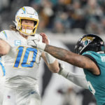 Los Angeles Chargers quarterback Justin Herbert (10) works in the pocket as Jacksonville Jaguars defensive end Roy Robertson-Harris (95) defends during the second half of an NFL wild-card football game, Saturday, Jan. 14, 2023, in Jacksonville, Fla. (AP Photo/Chris Carlson)