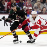Arizona Coyotes center Nick Schmaltz (8) passes the puck past Detroit Red Wings center Michael Rasmussen (27) during the second period of an NHL hockey game in Tempe, Ariz., Tuesday, Jan. 17, 2023. (AP Photo/Ross D. Franklin)