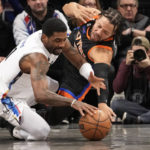 
              Brooklyn Nets guard Kyrie Irving, left, and New York Knicks guard Jalen Brunson fight for a loose ball during the first half of an NBA basketball game, Saturday, Jan. 28, 2023, in New York. (AP Photo/Mary Altaffer)
            