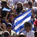 Supporters of Stefanos Tsitsipas of Greece hold his national flag during his semifinal against Karen Khachanov of Russia at the Australian Open tennis championship in Melbourne, Australia, Friday, Jan. 27, 2023. (AP Photo/Dita Alangkara)