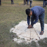 
              A man collects arrows that were thrown on white sand to declare the results, after the first round of an archery event in Shillong, India, Monday, Jan. 16, 2023. Each afternoon, except on Sundays and public holidays, this event takes place in a small field and people place bets on the results. (AP Photo/Ashwini Bhatia)
            