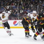 Chicago Blackhawks' Andreas Athanasiou, left, and Caleb Jones, right, celebrate Patrick Kane's goal as Vancouver Canucks' Tyler Myers (57) and Elias Pettersson (40) look away during the first period of an NHL hockey game Tuesday, Jan. 24, 2023, in Vancouver, British Columbia. (Darryl Dyck/The Canadian Press via AP)
