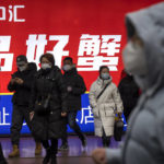 
              Commuters wearing face masks walk out of a subway station in the central business district in Beijing, Thursday, Jan. 12, 2023. (AP Photo/Mark Schiefelbein)
            